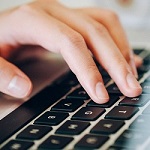 Photo of hands typing on a computer keyboard